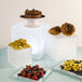 A table with three American Metalcraft frosted acrylic cube risers holding desserts including a cake, strawberries, and blueberries.