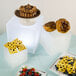 A table with a group of desserts and fruit displayed on white cube risers.