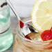 An Arcoroc stainless steel iced tea spoon in a jar with a lemon slice and lemon.