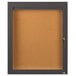 A bronze Aarco indoor bulletin board cabinet with a glass door and key lock.
