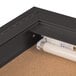 A black bulletin board cabinet with a light inside.