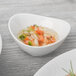 A Schonwald Grace white porcelain dip dish filled with food on a table.