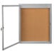 A corkboard with a white door and a silver frame.