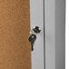 A satin anodized Aarco bulletin board cabinet with a key in the lock.