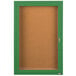 An Aarco green powder coated enclosed bulletin board cabinet with a cork board and glass door with a key.