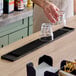 A long black bar mat with a textured surface, shown on a countertop with two upside-down glasses.