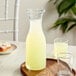A Libbey wine decanter filled with a glass of liquid on a table.