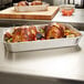 A Vollrath aluminum roasting pan filled with cooked chicken and vegetables on a counter.