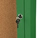 A key in a keyhole unlocking a green Aarco indoor bulletin board cabinet.