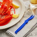 A lobster on a plate with a blue Seafood Sheller and a lemon.