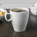 A close up of a white Schonwald Grace porcelain cup with a brown liquid in it.