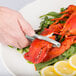 A hand using a Choice lobster cracker to crack a lobster shell.