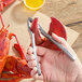 A stainless steel double-jaw lobster cracker being used to crack a lobster claw.