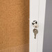 A white Aarco bulletin board cabinet with a key in the door lock.