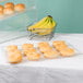 A Cal-Mil shallow clear bakery tray holding doughnuts and bananas on a bakery display counter.