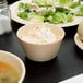 A Nustone Tan Melamine bouillon bowl filled with soup on a table.