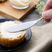 A person spreading butter on a piece of bread with a Chef & Sommelier stainless steel butter spreader.