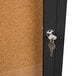 A black Aarco bulletin board cabinet with a key in the lock.