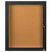 A black framed enclosed bulletin board with a glass door and key.