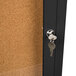 A black Aarco enclosed bulletin board cabinet with a key in the lock.
