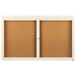 An Aarco ivory bulletin board cabinet with two cork boards behind glass doors.