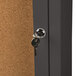 The bronze door of an Aarco lighted bulletin board cabinet with a key in the lock.