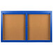 A blue framed bulletin board with two doors and a brown board.