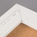A white indoor bulletin board cabinet with a cork board inside.