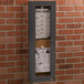 An Aarco bronze indoor bulletin board cabinet with a menu inside on a bulletin board.