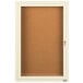 An ivory Aarco enclosed bulletin board cabinet with a door.