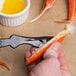 A person using a Choice Shuckaneer seafood sheller to open a crab claw.