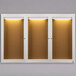 An Aarco white indoor lighted bulletin board cabinet with three doors.