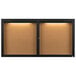 A black Aarco enclosed bulletin board cabinet with lights on.