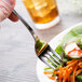 A Chef & Sommelier stainless steel salad fork on a plate of salad.