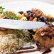 A plate of food with a Chef & Sommelier stainless steel dinner knife cutting meatballs.