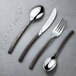 A Chef & Sommelier stainless steel soup spoon on a table next to a knife.