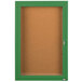 A green framed Aarco indoor bulletin board cabinet with a cork board and a glass door with a key.