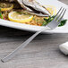 A plate of food with a fish fork and lemon slices.