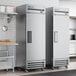 A room in a school kitchen with two True stainless steel reach-in refrigerators.