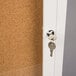 A key in the door lock of a white Aarco bulletin board cabinet.