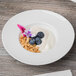 A Schonwald white porcelain bowl filled with yogurt, blueberries, and granola.