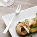 An Arcoroc stainless steel escargot fork on a plate with a snail shell.