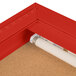 A red indoor bulletin board cabinet with a white interior and light.