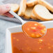 A Libbey stainless steel bouillon spoon holding soup over a bowl.