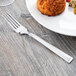 A Libbey stainless steel dinner fork on a plate of food.