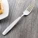 A Libbey stainless steel dessert fork on a white plate.