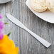 A Libbey stainless steel butter spreader on a plate next to a biscuit.