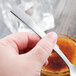 A person holding a Libbey stainless steel teaspoon over a bowl.