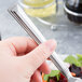 A hand holding a Libbey stainless steel salad fork over a salad