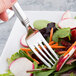 A Libbey stainless steel salad fork on a plate of salad.